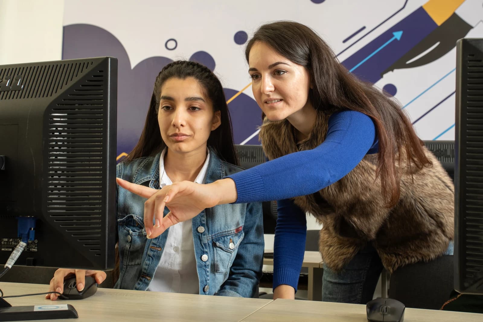 Trainer instructs data annotator on how to label images on a computer.