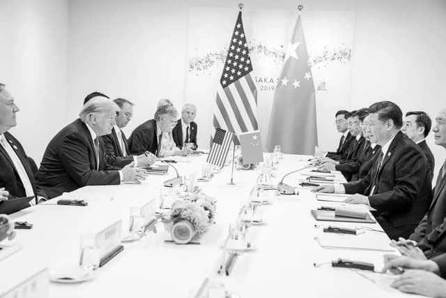 Donald Trump and Xi Jinping seated at a long conference table with delegations.