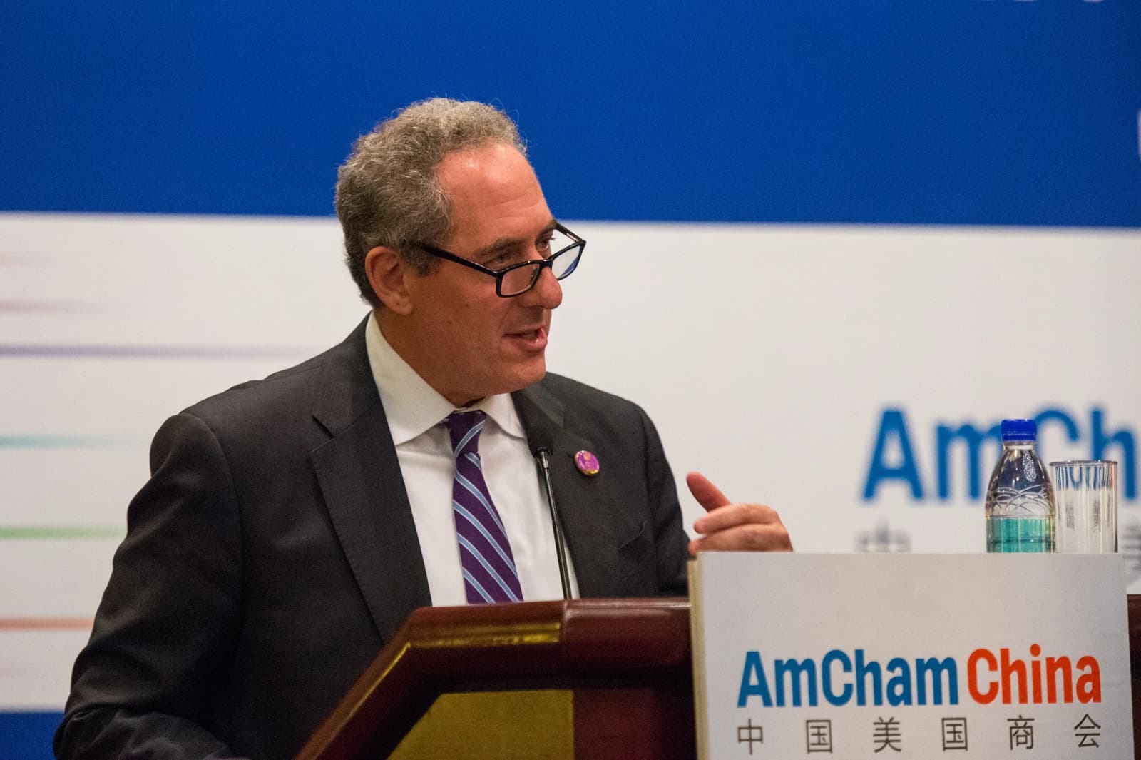 Ambassador Michael Froman speaking at a podium with AmCham China sign.
