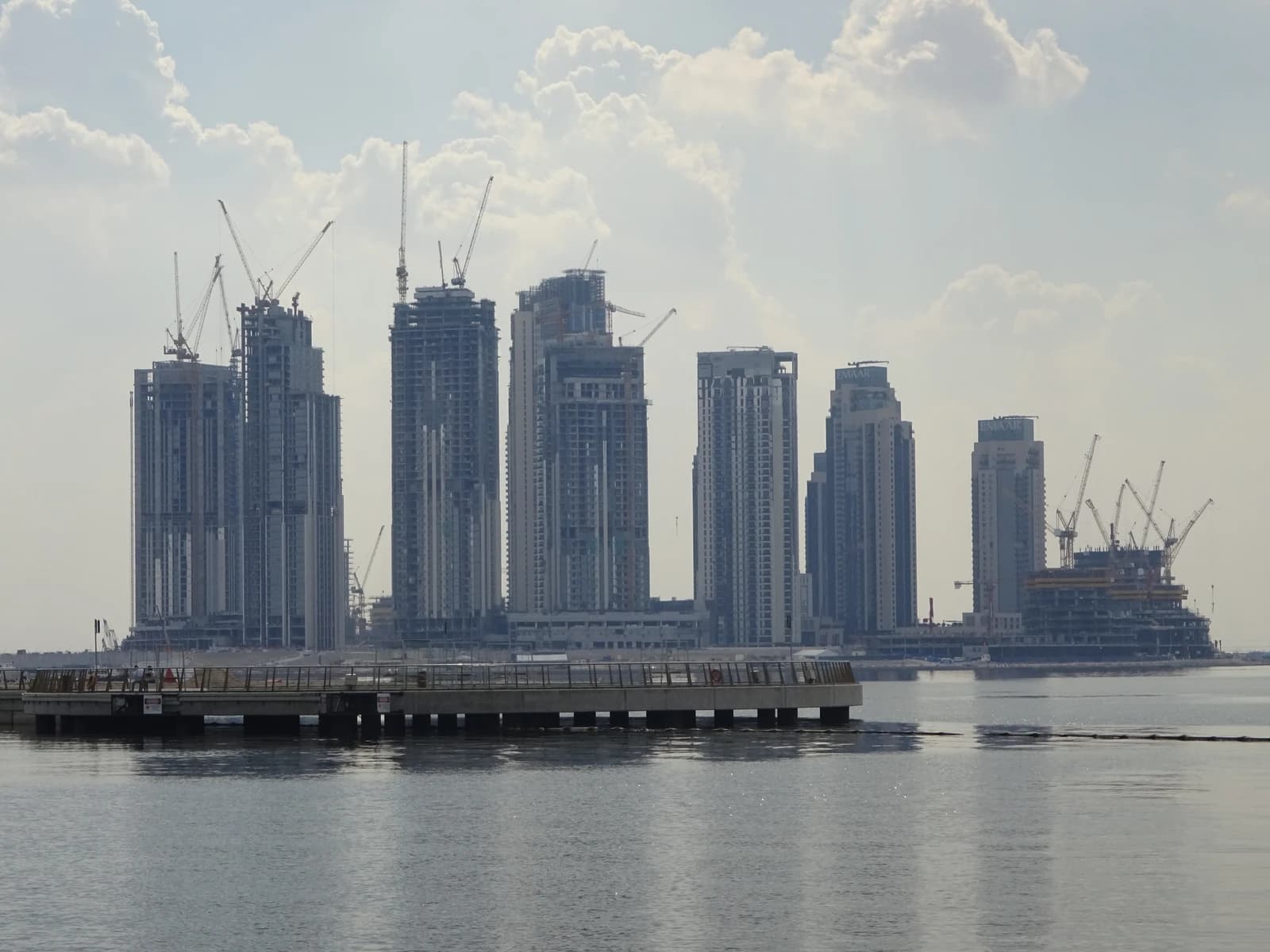 New buildings under construction with many cranes along Dubai Creek.
