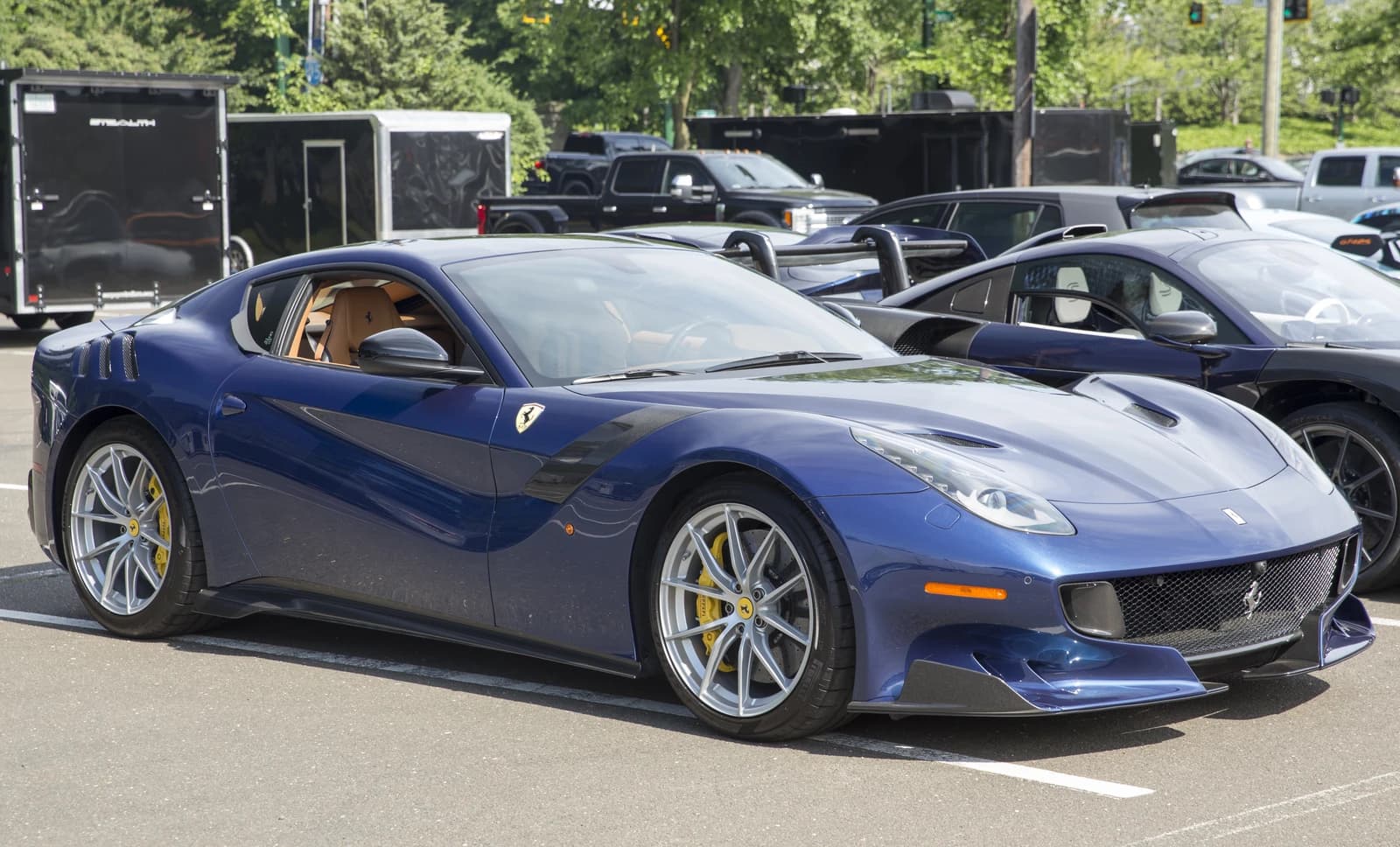 A blue 2017 Ferrari F12tdf is parked outdoors on an asphalt surface.