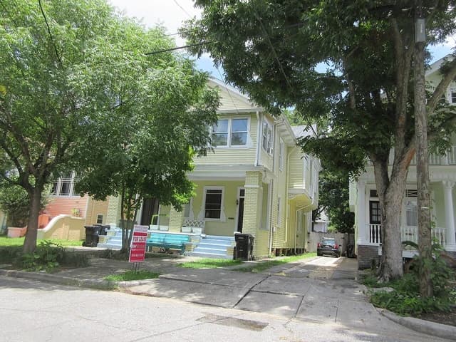 Yellow house in Uptown New Orleans with a "For Lease" sign in the yard.