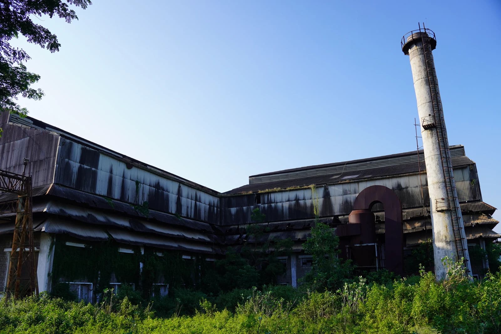 Side view of the Viziangaram cooperative sugars factory building and smokestack against a blue sky.