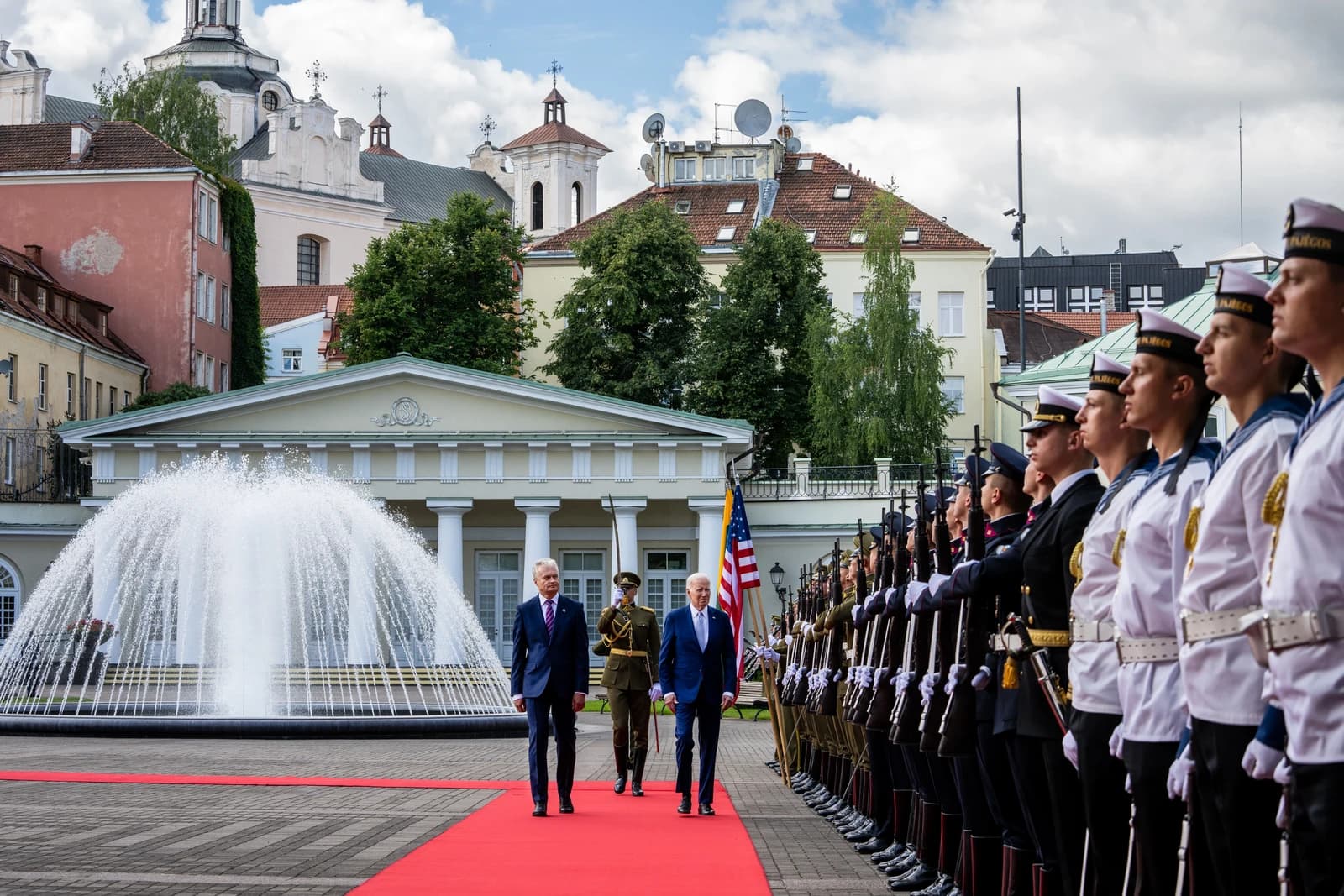 Gitanas Nausėda and Joe Biden walk on red carpet past uniformed soldiers.