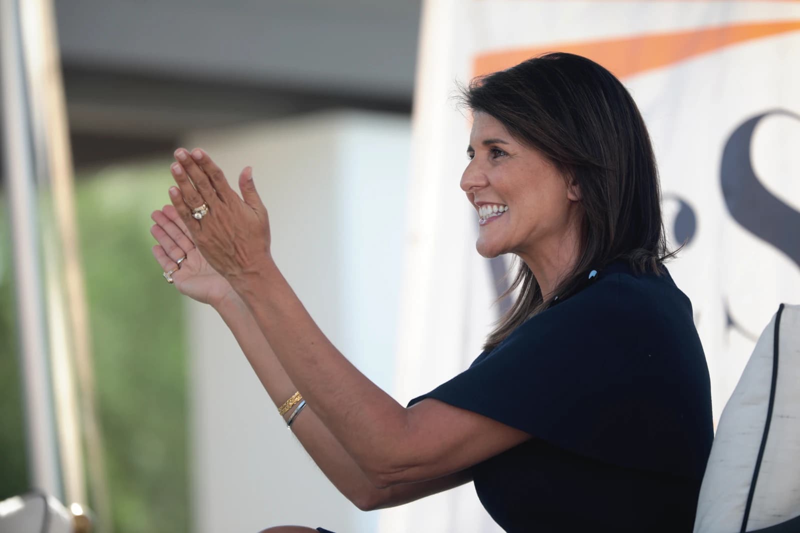 Nikki Haley, former US Ambassador to the UN, smiling and clapping at an event.