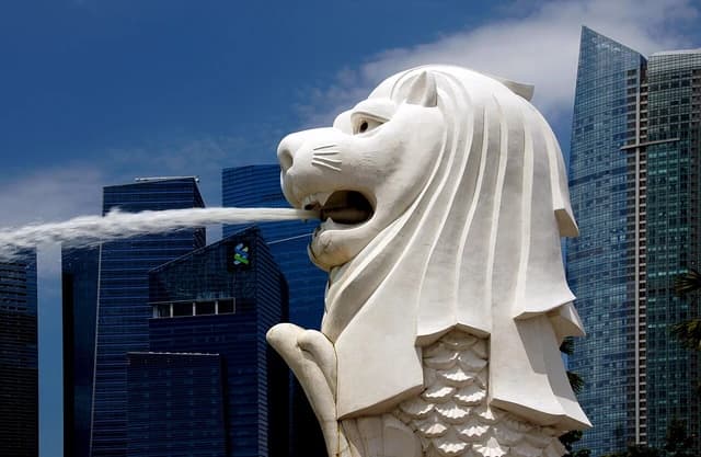 The Merlion statue spouting water in front of modern skyscrapers.