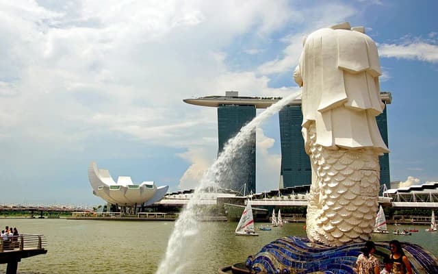 Merlion statue spouting water with the Marina Bay Sands hotel and ArtScience Museum in the background.