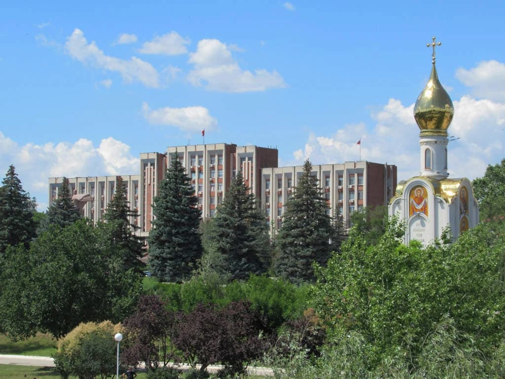 Supreme Council of Transnistria building and a church dome against a blue sky.