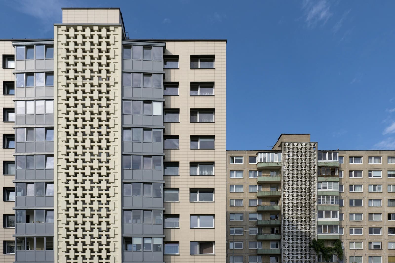Facades of modern apartment buildings with patterned panels and windows in a city.