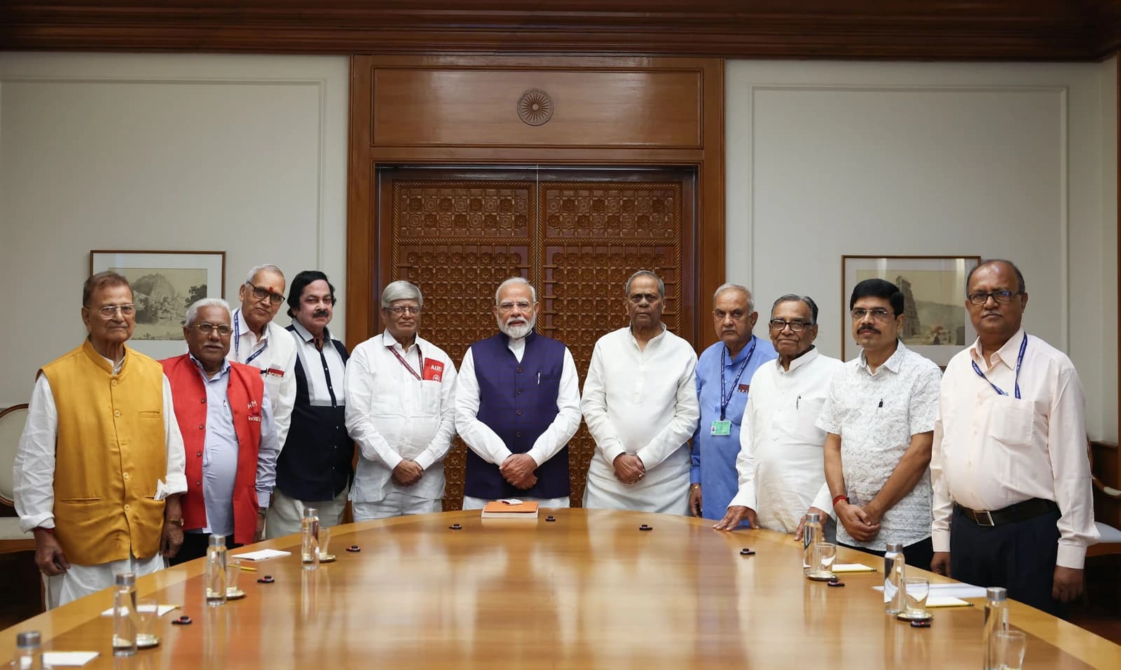 Indian Prime Minister Narendra Modi stands with a group of men in a meeting room.