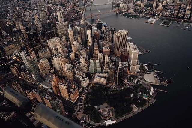 Aerial view of Lower Manhattan and Battery Park at dusk, showing skyscrapers and waterfront.