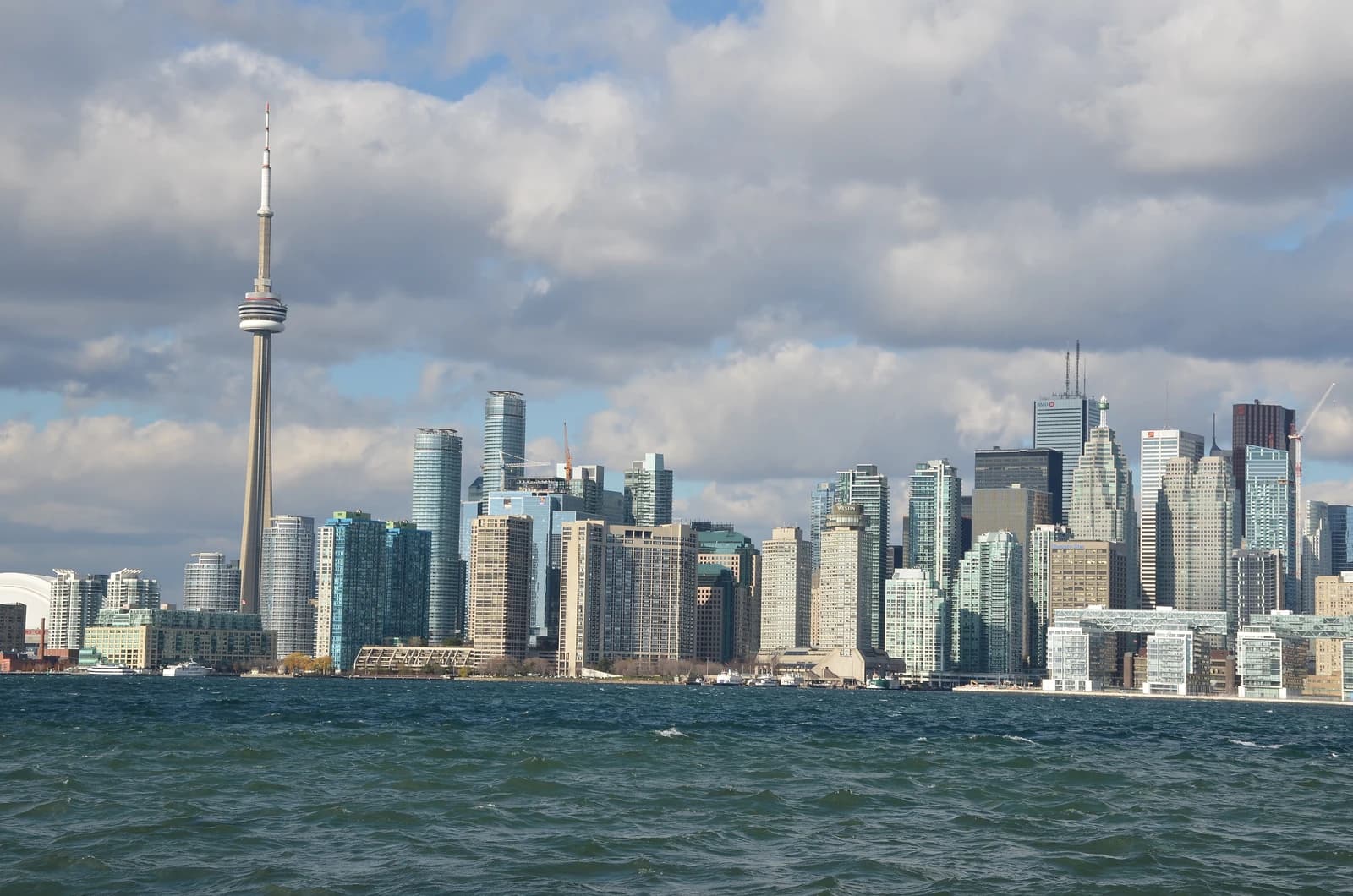 Toronto skyline featuring the CN Tower and numerous high-rise buildings across a body of water.