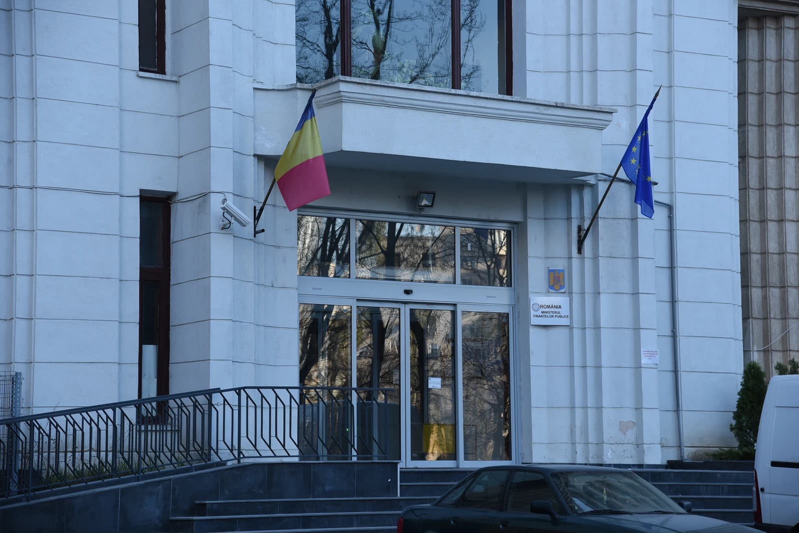 Exterior view of the Romanian Ministry of Public Finance building with Romanian and EU flags.