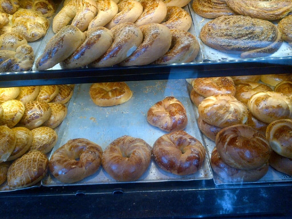 Turkish pastries and bread, including açma, poğaça, and çörek, on display shelves.