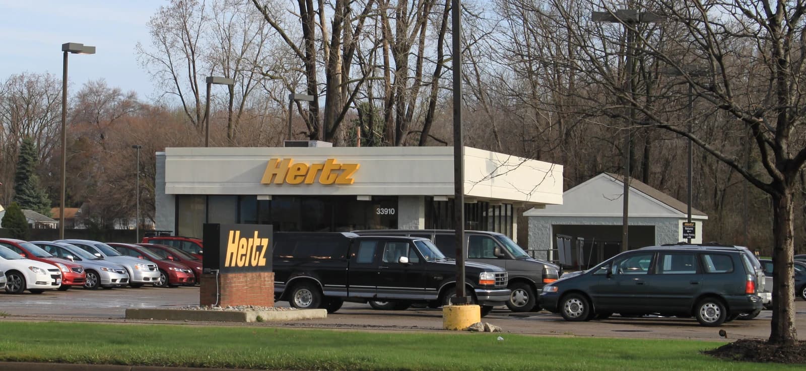 Hertz car rental office building with several vehicles parked in front.