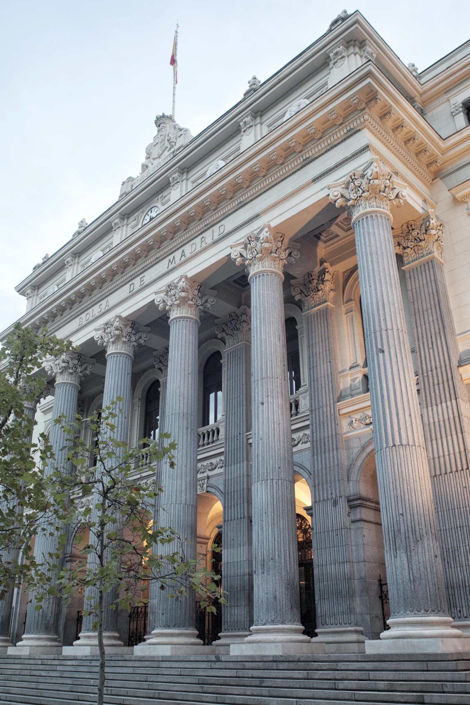 Grand neoclassical facade of the Madrid Stock Exchange building with tall columns.