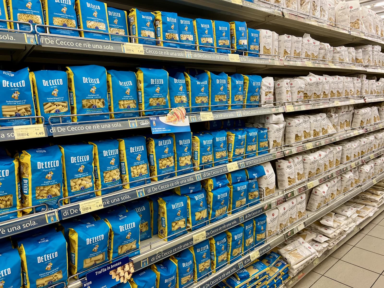 Dry pasta packages displayed on shelves in a grocery store.