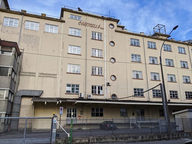 Pastificio Corticella building, a multi-story light-colored factory with many windows and a gate.