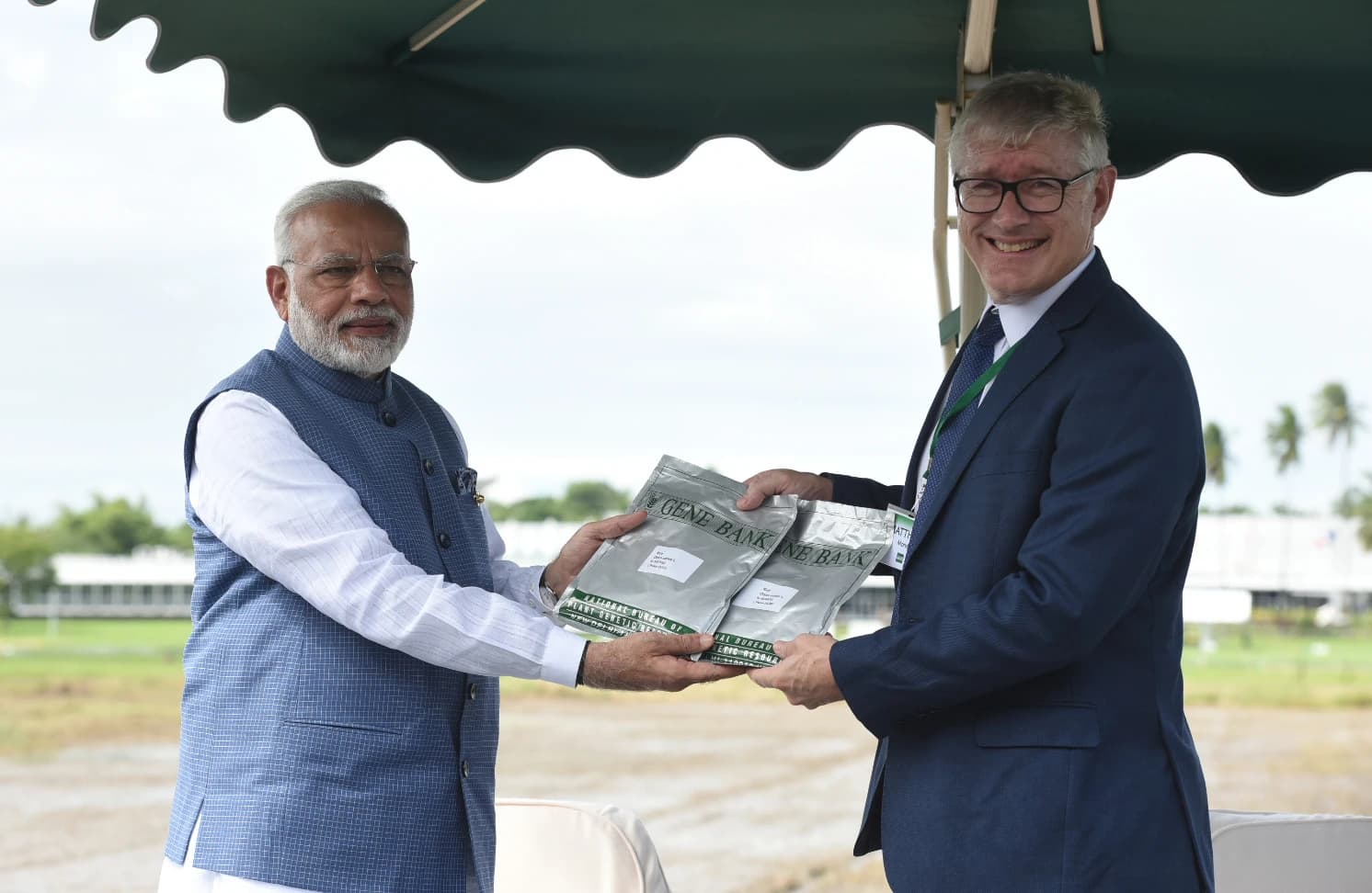 Narendra Modi, Prime Minister of India, presenting two rice seed packets to a man.