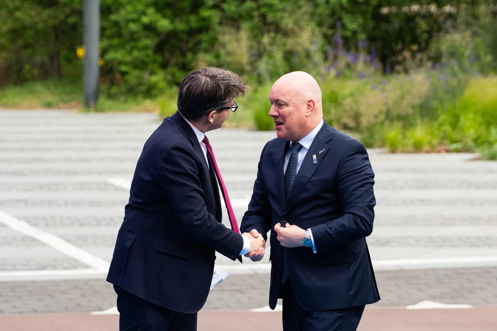New Zealand Prime Minister Christopher Luxon shaking hands with an unknown delegate at a summit.