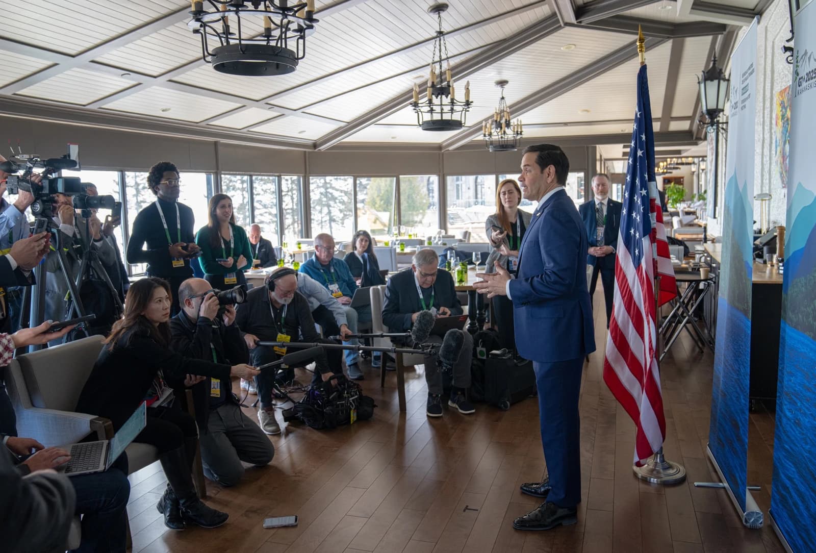 Secretary of State Rubio speaking at a press conference with reporters and cameras.