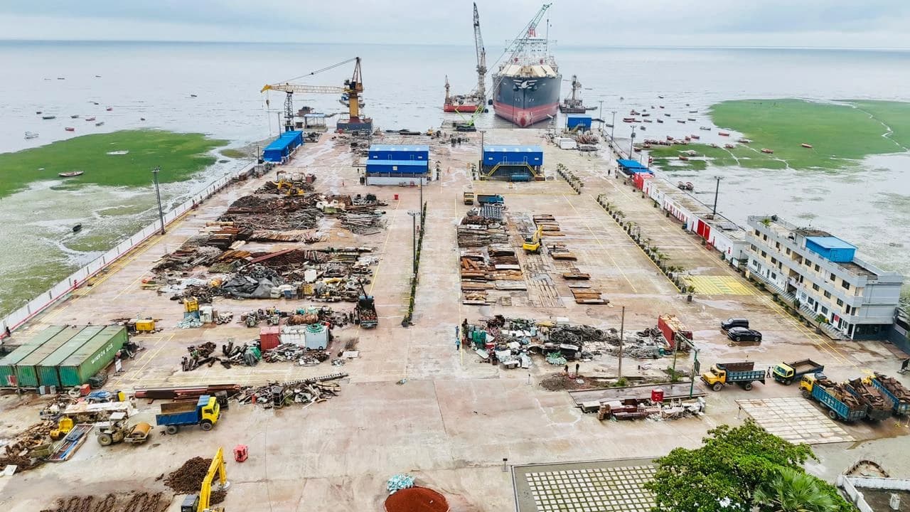Aerial view of a ship recycling yard with ships, cranes, and materials.