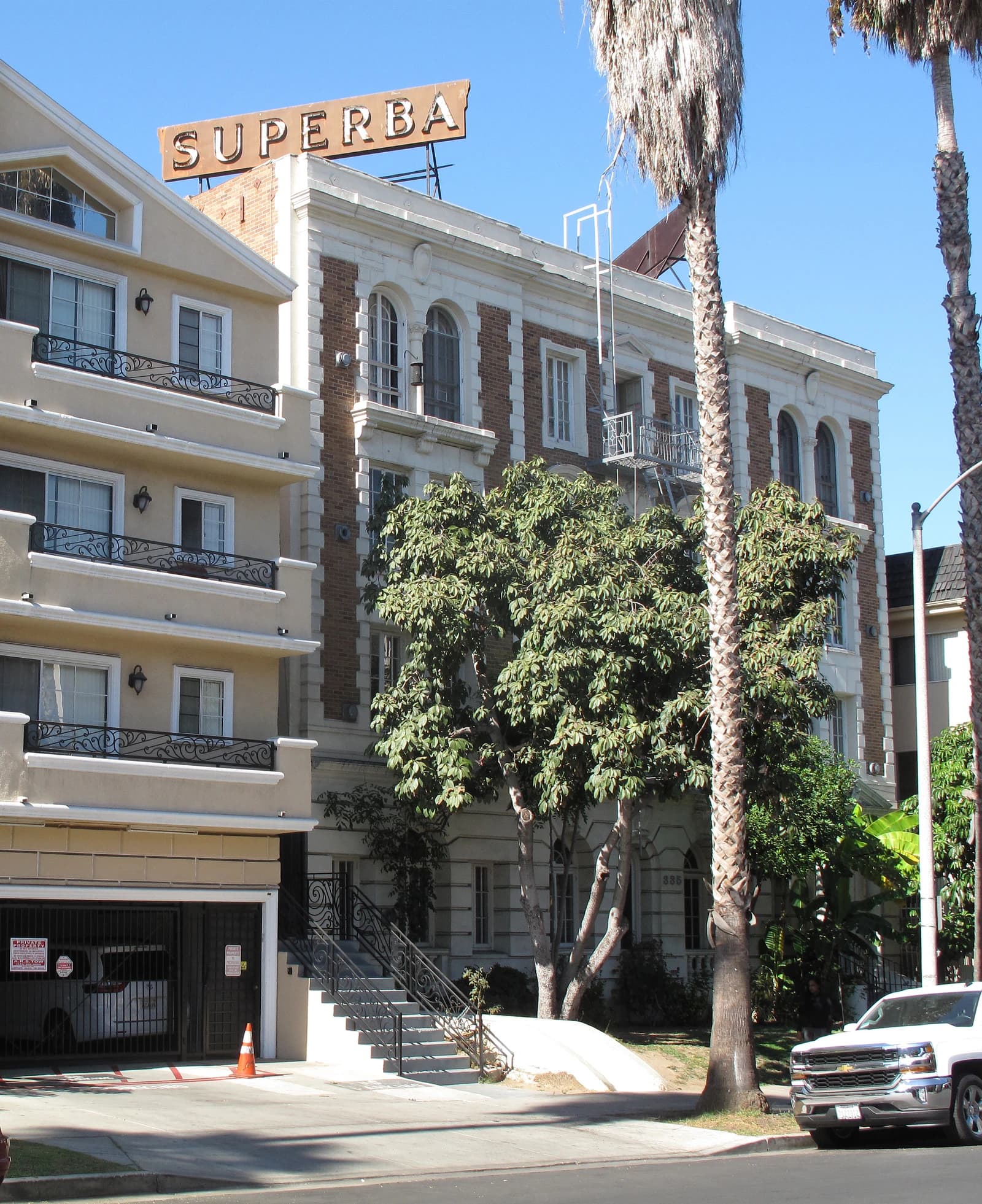 Superba Apartments building in Los Angeles, with palm trees in the foreground.