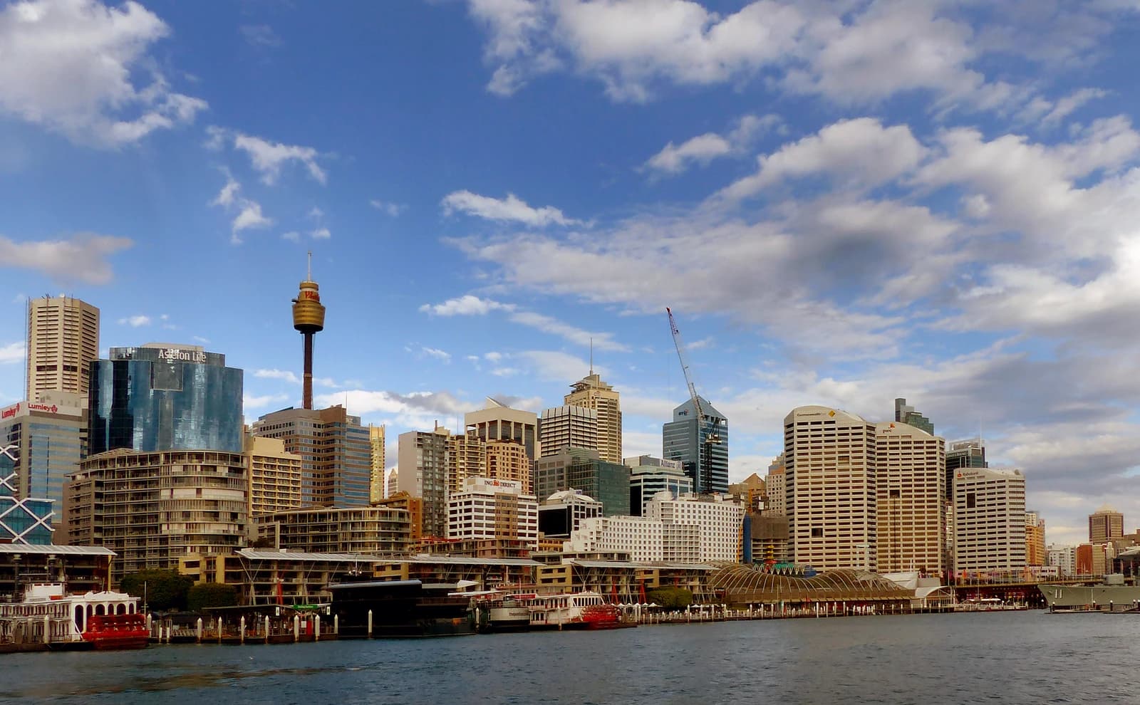 Sydney skyline with numerous office buildings and the iconic Sydney Tower rising against a blue sky.