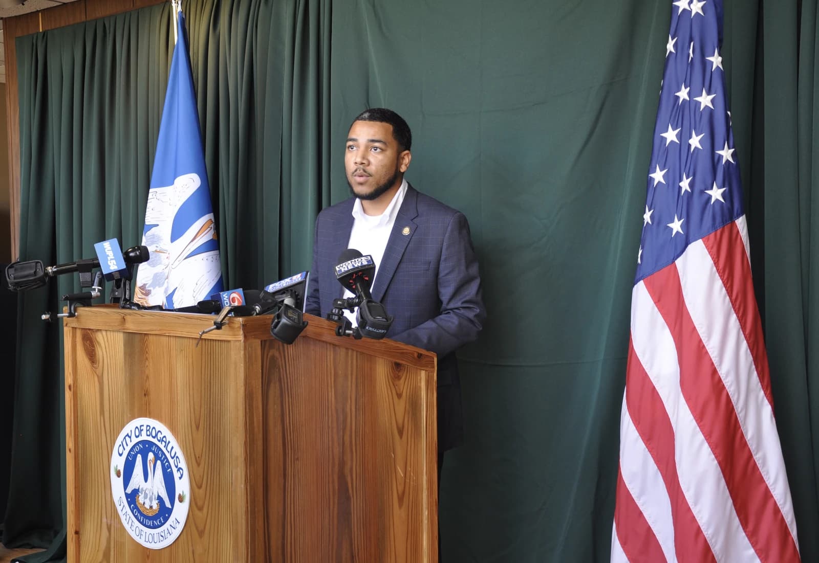 Bogalusa Mayor Tyrin Truong at a press conference podium with microphones.