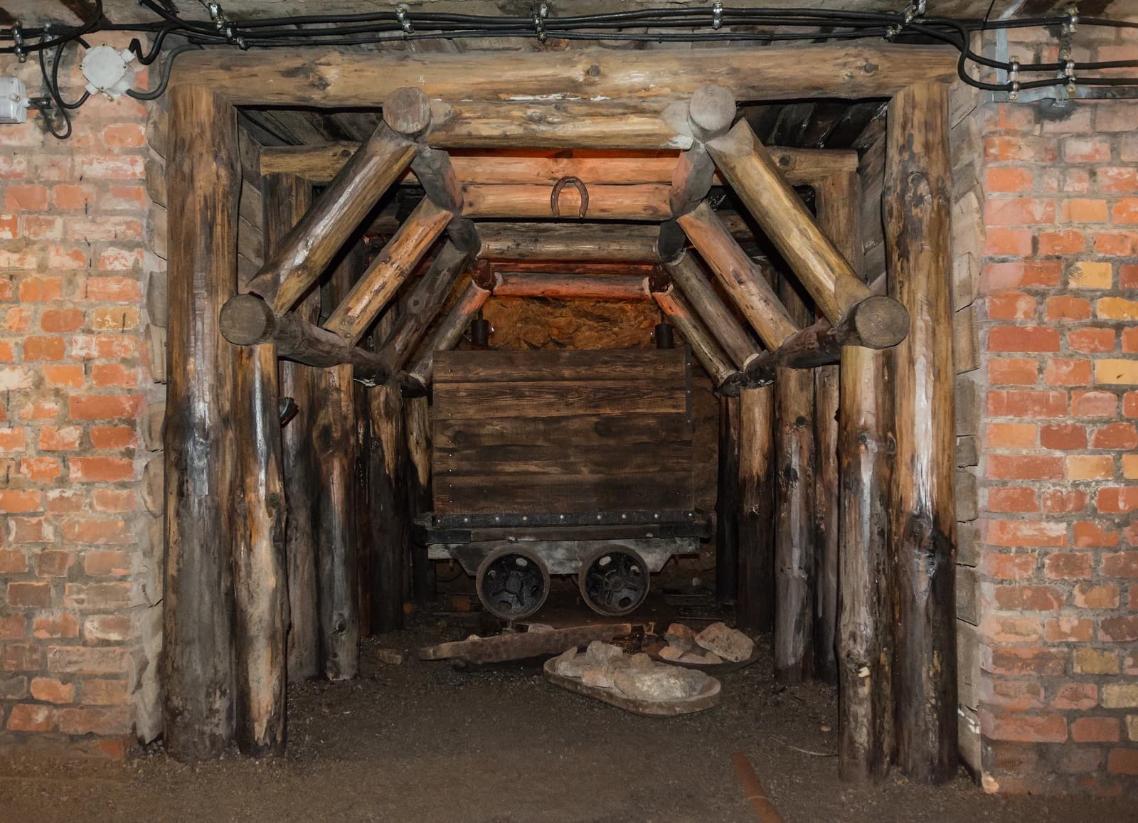 An old wooden mining cart sits inside a supported mine tunnel.
