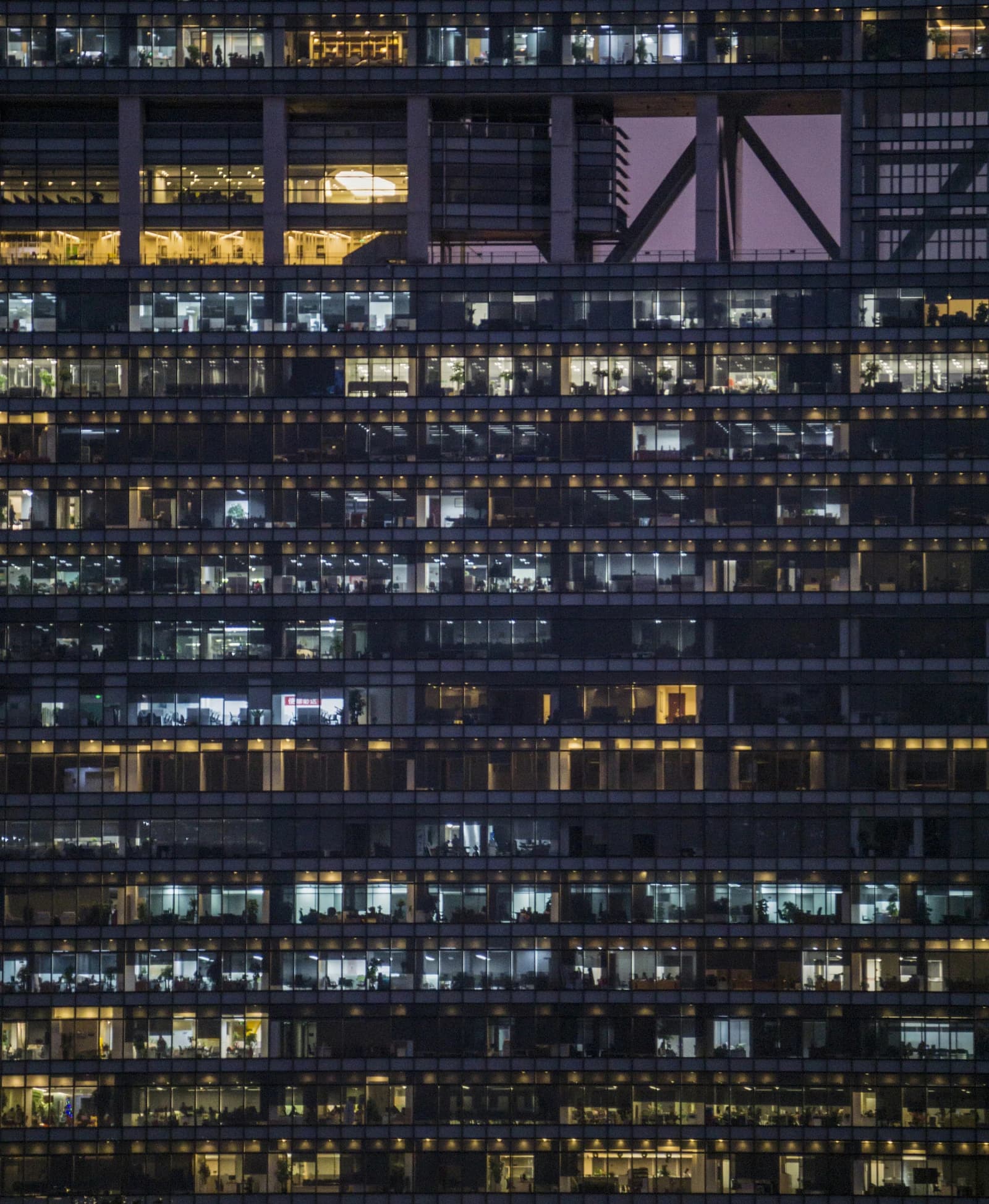 Exterior of an office building at night with many illuminated windows.