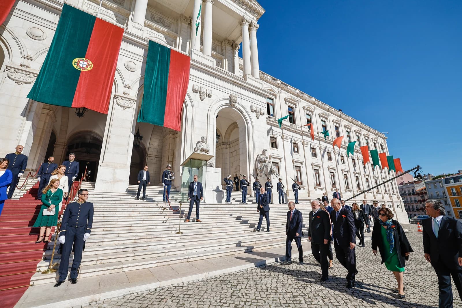 Luiz Inácio Lula da Silva, President of Brazil, walks on a cobblestone street in front of a grand building.