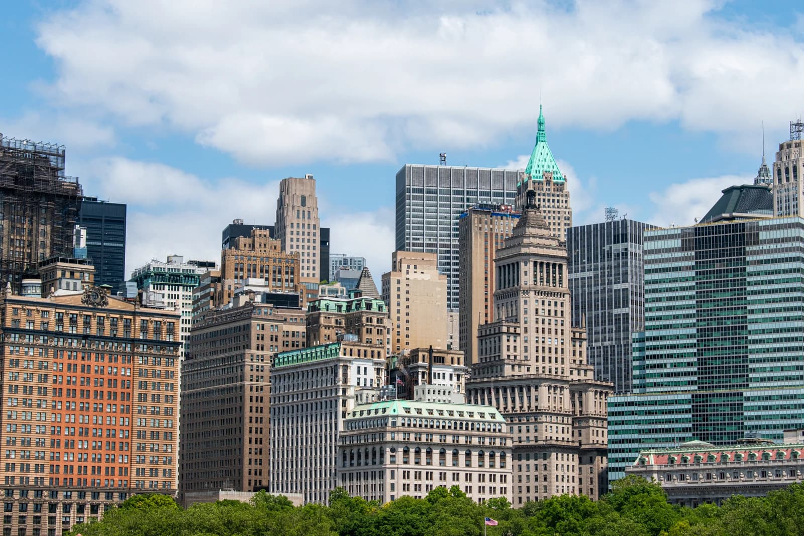 Skyline of a major financial district with numerous tall buildings under a partly cloudy sky.
