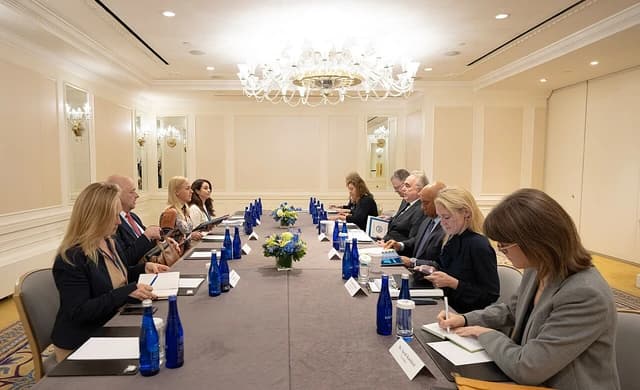 People seated at a long conference table, engaged in a meeting.