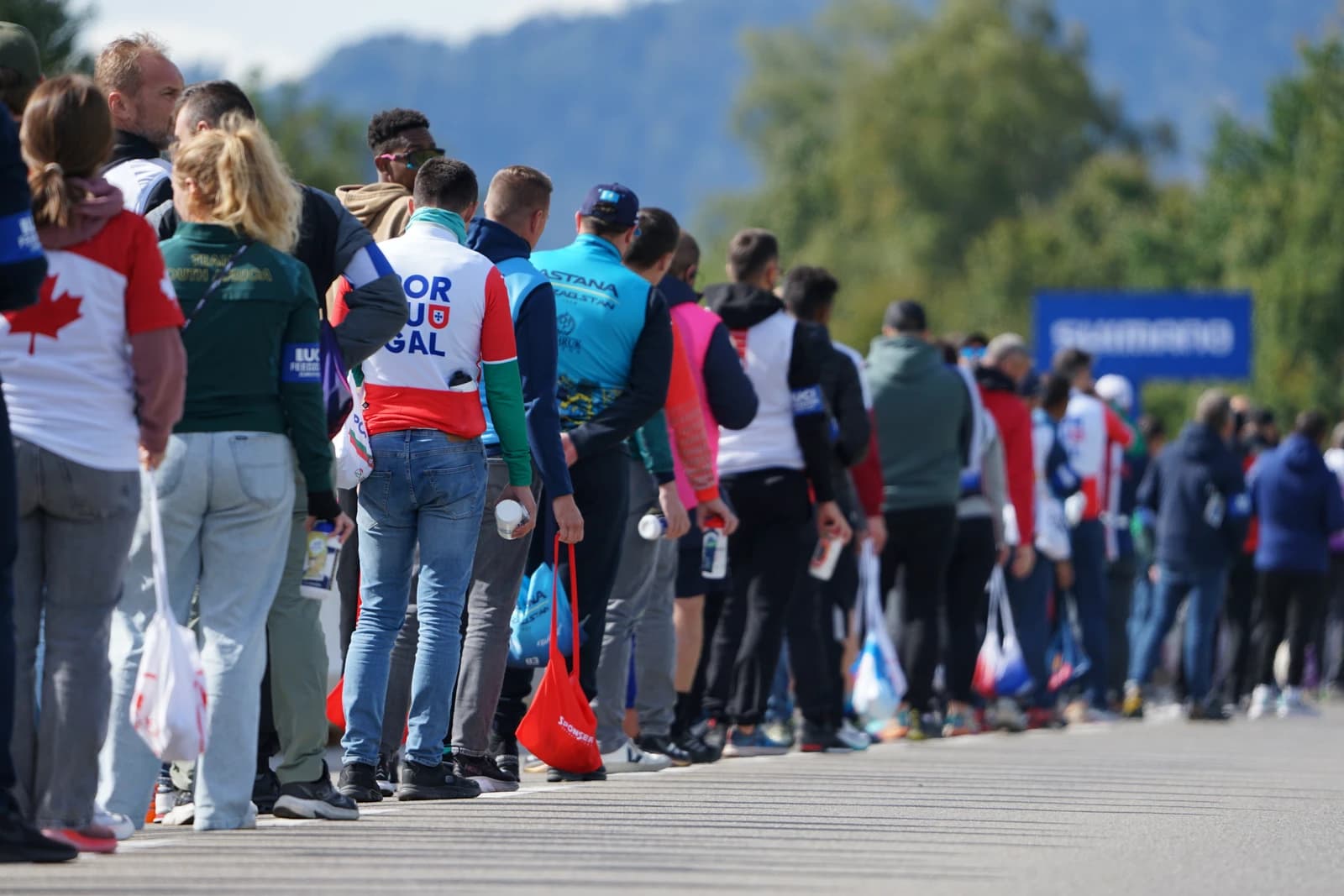People in a line, many wearing national team apparel, at a cycling event.