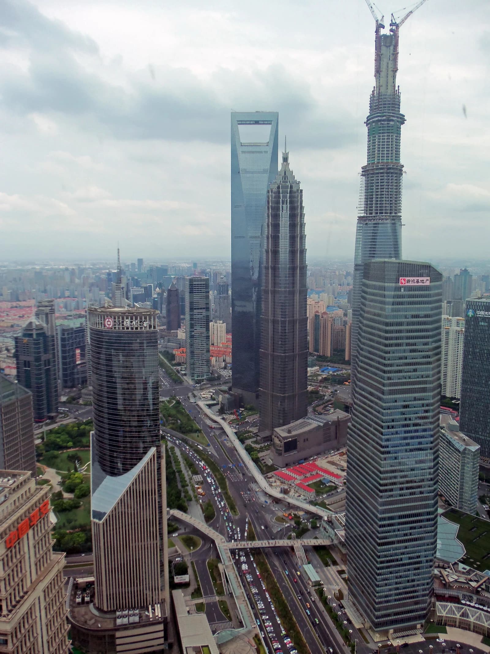 Aerial view of the Lujiazui financial district skyline with multiple skyscrapers and a busy road.