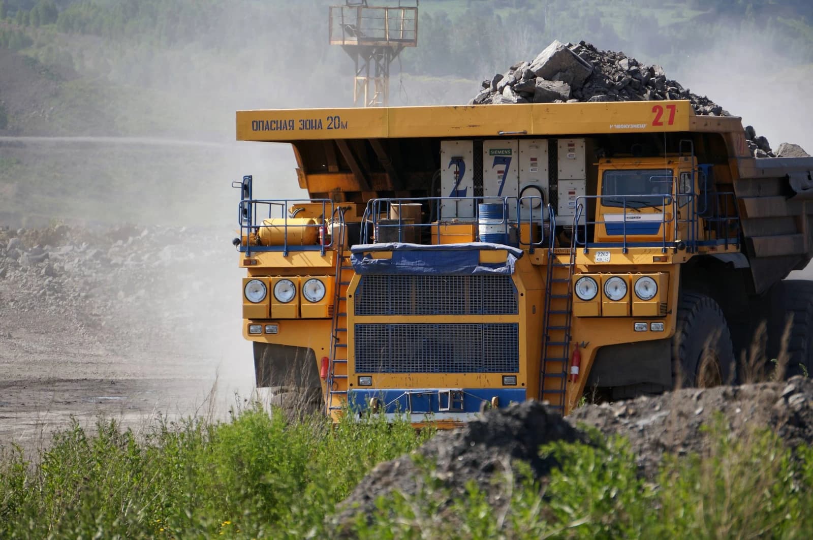 Large yellow BelAZ 75600 mining truck carrying a full load of coal at an open-pit mine.
