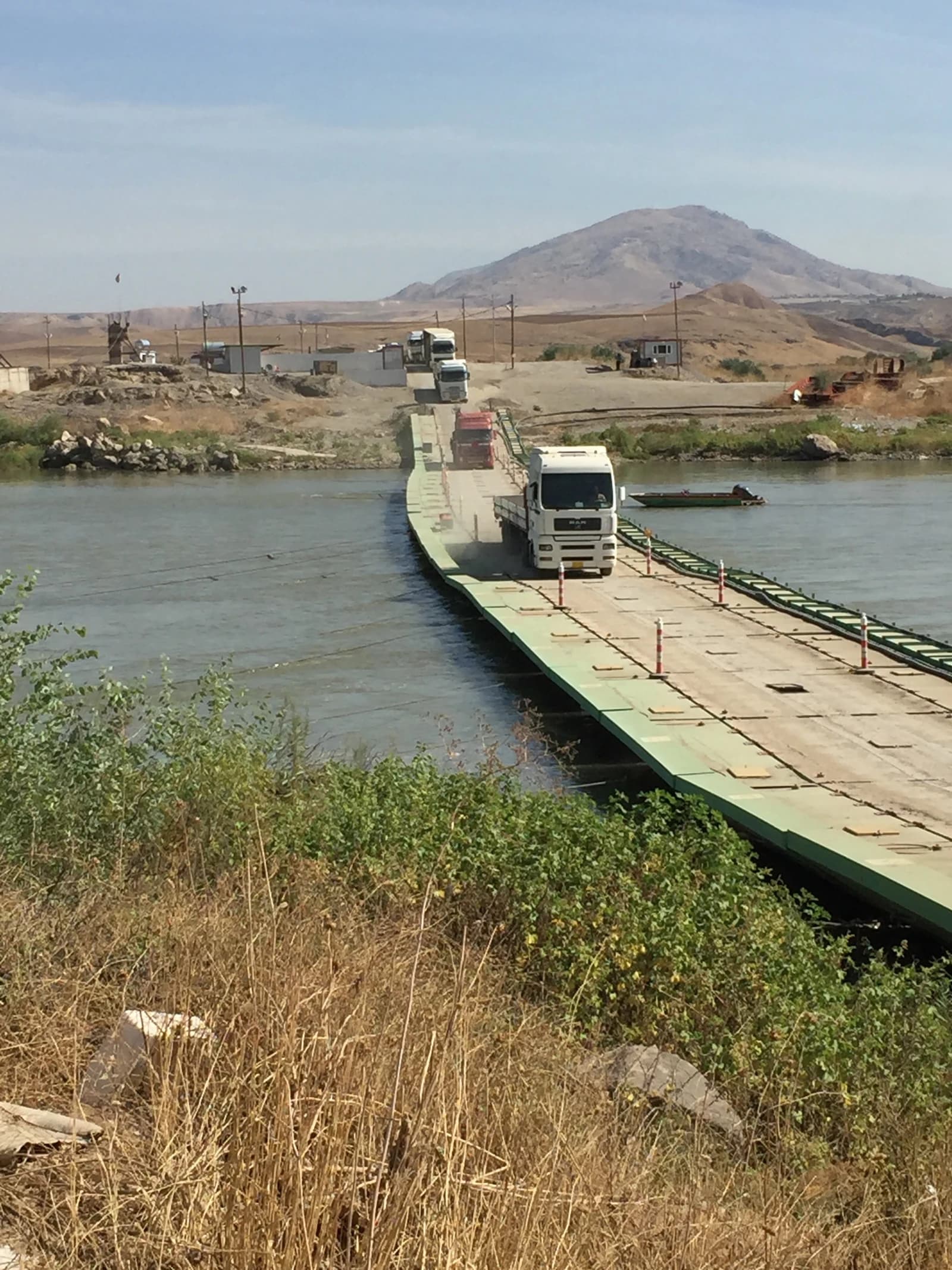 Trucks crossing a pontoon bridge over a river at the Semalka border point.