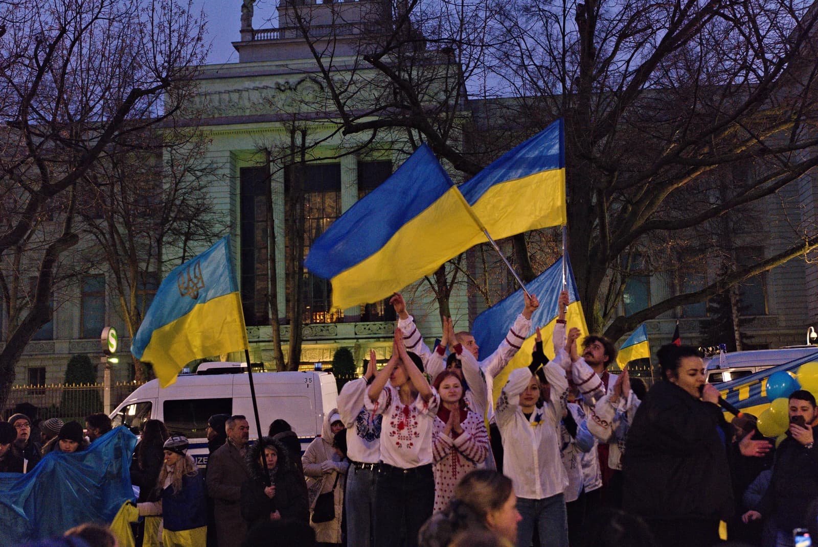 People holding Ukrainian flags gathered in front of a building in Berlin.