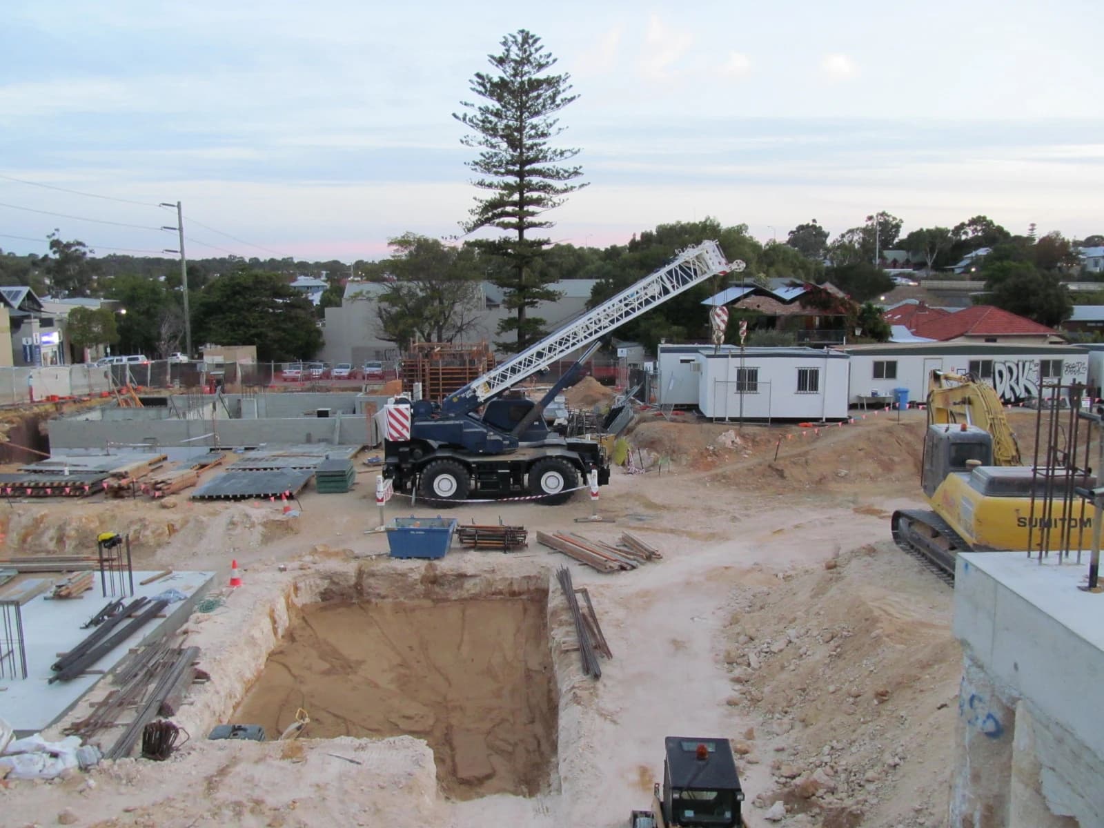 Construction site in Fremantle, Australia, showing foundation work, crane, and excavators.