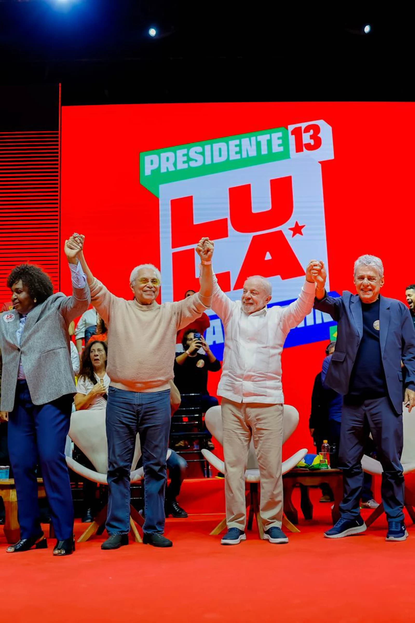 Lula da Silva, center, stands with three other people, all raising their clasped hands.