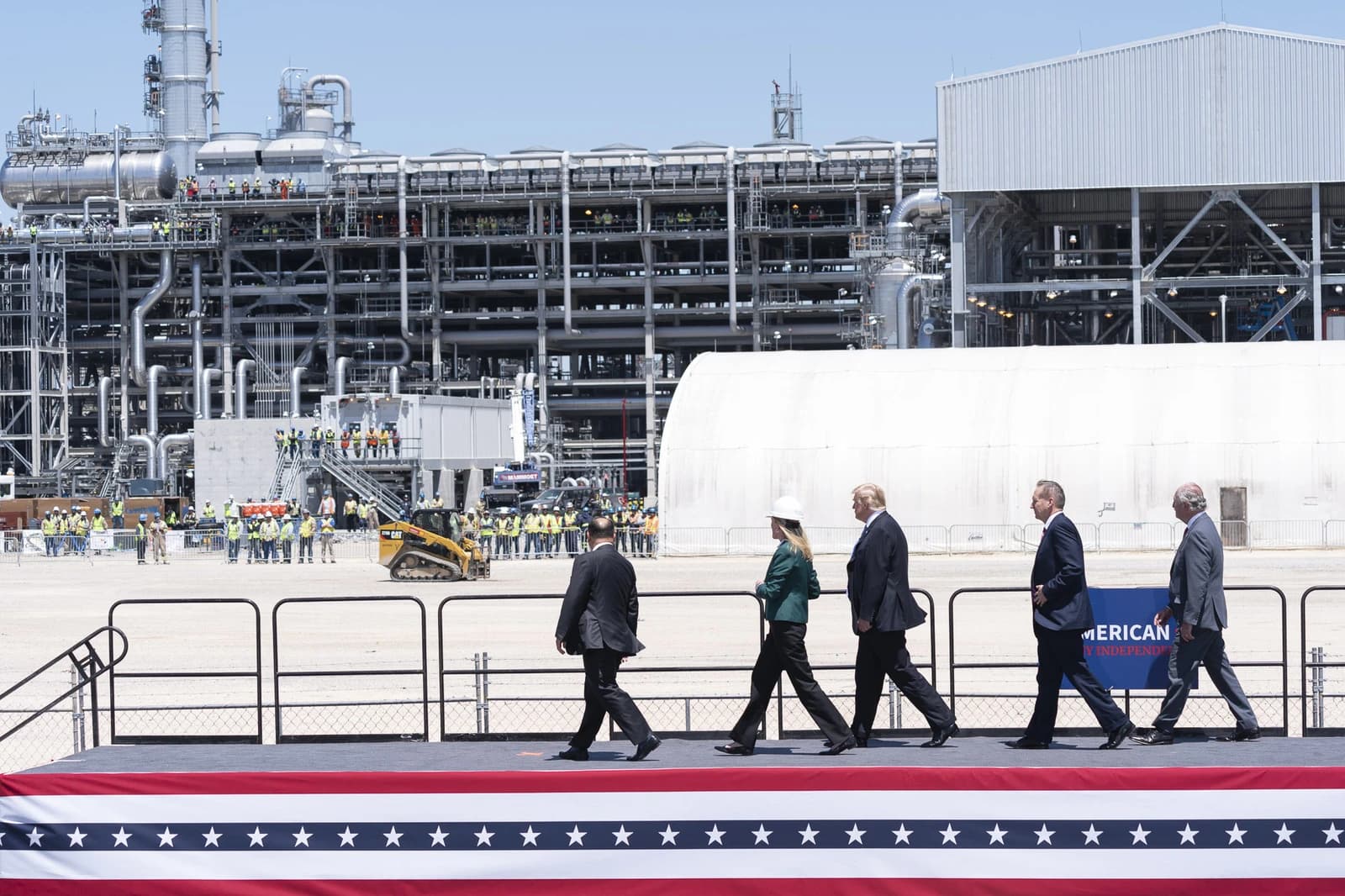 President Trump and officials walk past industrial complex at Cameron LNG Export Terminal.
