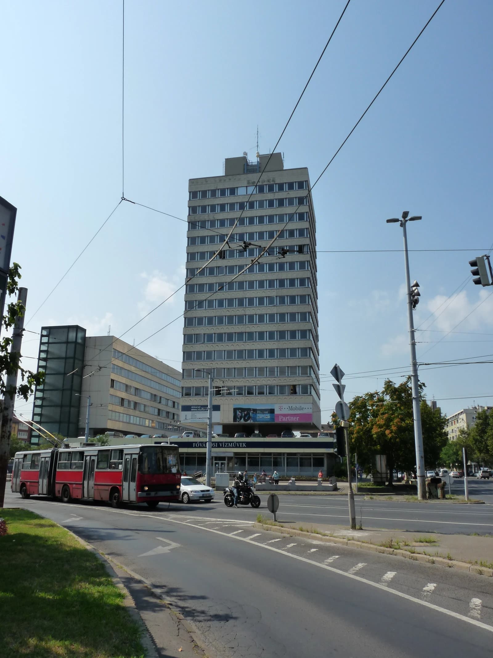 Headquarters building of Fővárosi Vízművek and a street with a trolleybus and traffic in Budapest.