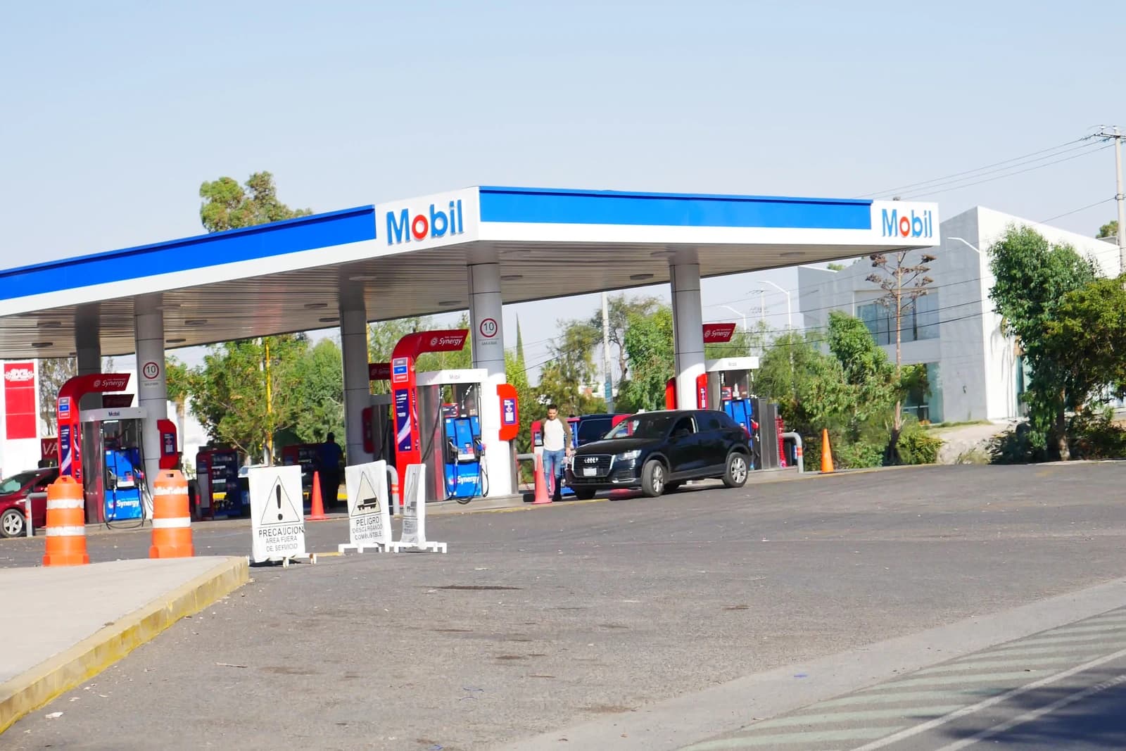 Exterior view of a Mobil gas station with a black car at the pumps.