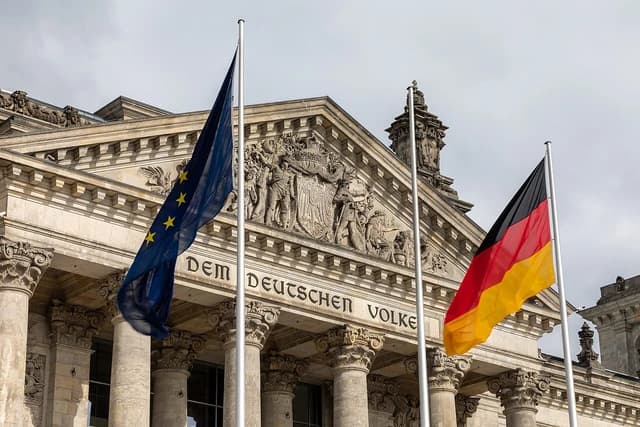 Reichstag Building facade in Berlin with German and European Union flags flying.