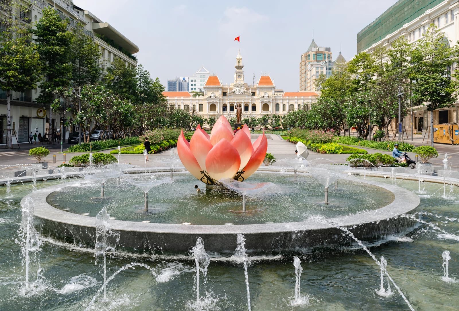Fountain with lotus sculpture on Nguyen Hue Street, Ho Chi Minh City, with the City Hall building in the background.