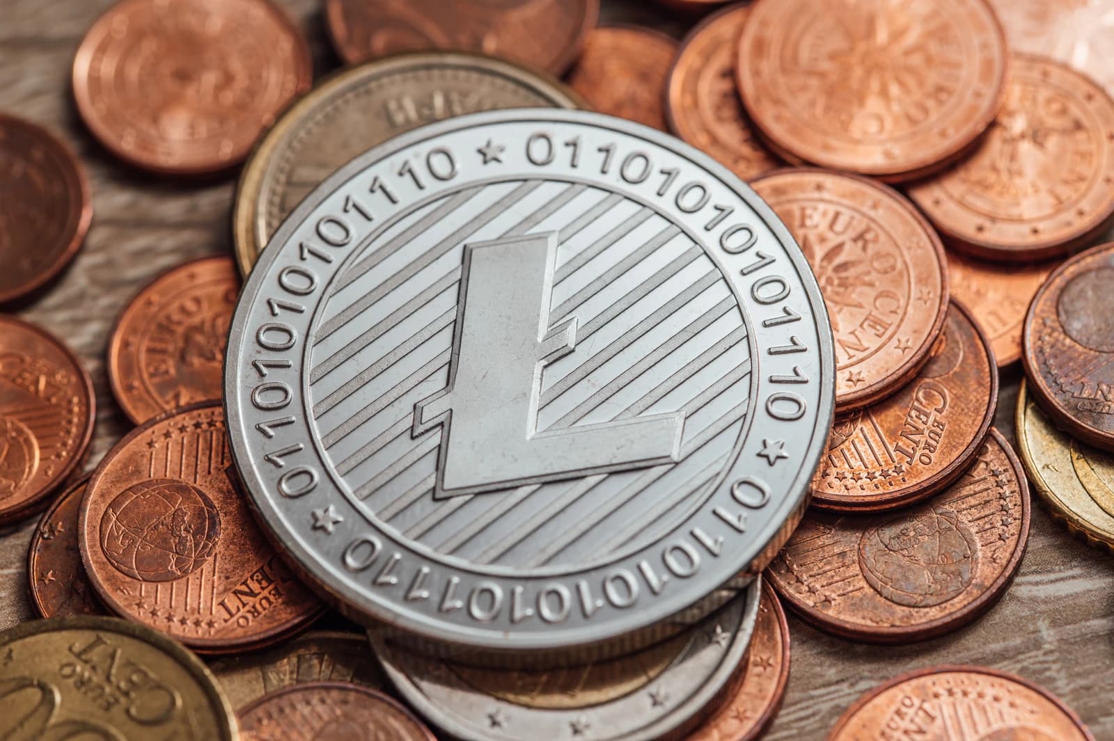 Close-up of a physical Litecoin coin, surrounded by other metallic coins.