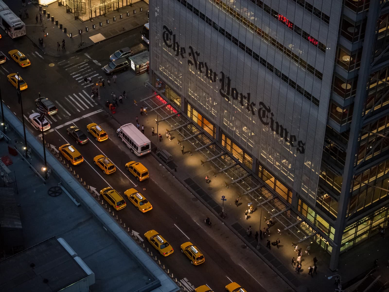 Aerial view of The New York Times building facade and busy street at dusk.