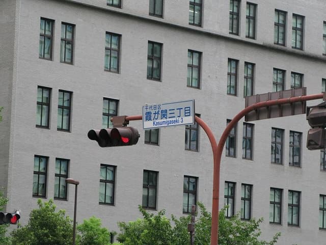 Japan's Ministry of Finance building facade with windows and a street sign on a pole.
