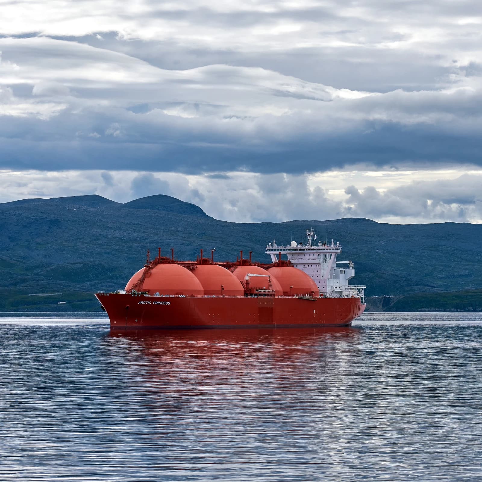 LNG carrier Arctic Princess sailing through calm waters with mountains in the background.